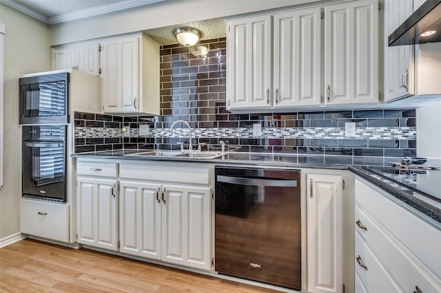 kitchen with dark countertops, black appliances, range hood, and a sink