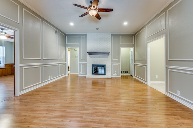 unfurnished living room featuring a ceiling fan, light wood-type flooring, a fireplace, and a decorative wall