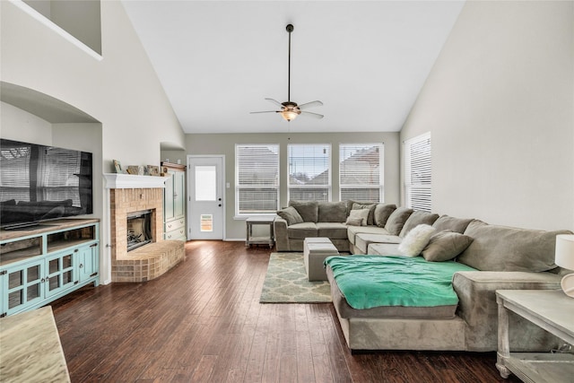 living area featuring ceiling fan, a fireplace, high vaulted ceiling, and dark wood-style flooring