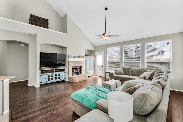 living area featuring a wealth of natural light, dark wood-style flooring, a fireplace, and ceiling fan