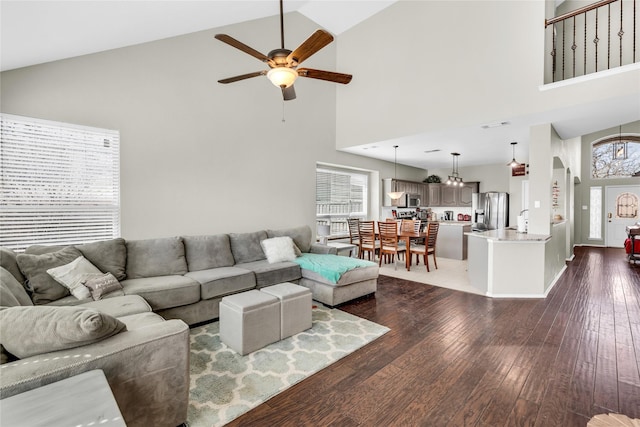 living area with high vaulted ceiling, a ceiling fan, and dark wood-type flooring