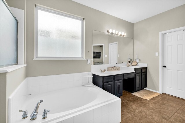 bathroom featuring double vanity, a garden tub, tile patterned flooring, and a sink