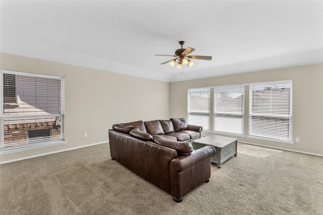 carpeted living area with a ceiling fan and baseboards