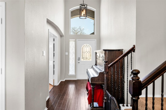 foyer entrance featuring a towering ceiling, stairs, baseboards, and dark wood finished floors