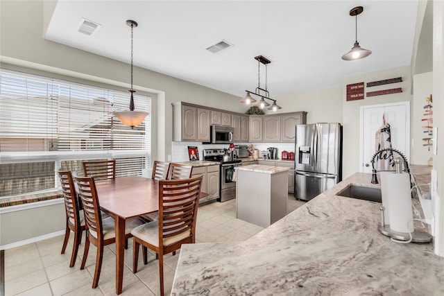 kitchen featuring stainless steel appliances, a sink, visible vents, a center island, and pendant lighting