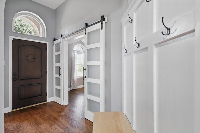 foyer featuring a barn door, dark wood-type flooring, and baseboards