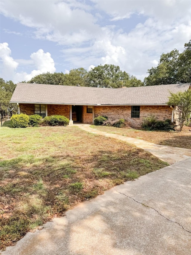 ranch-style home with brick siding, a shingled roof, and a front yard