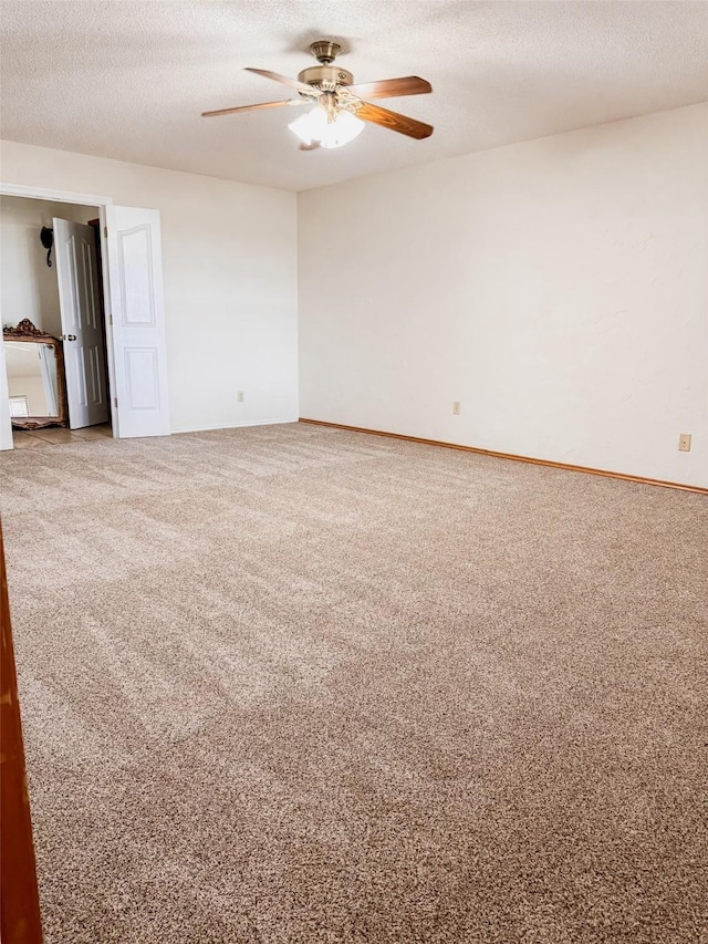 carpeted empty room featuring ceiling fan, baseboards, and a textured ceiling