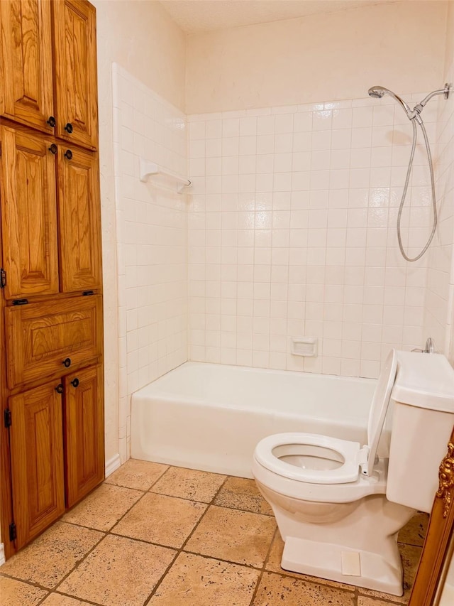 bathroom featuring toilet, shower / bath combination, and stone tile flooring