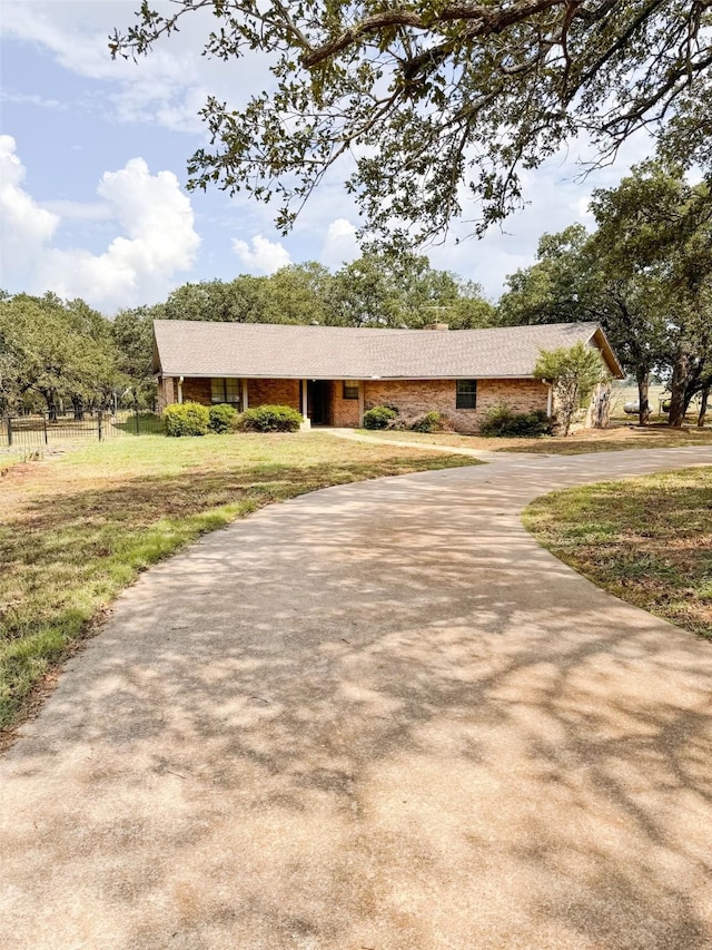 single story home featuring driveway, fence, a front lawn, and brick siding