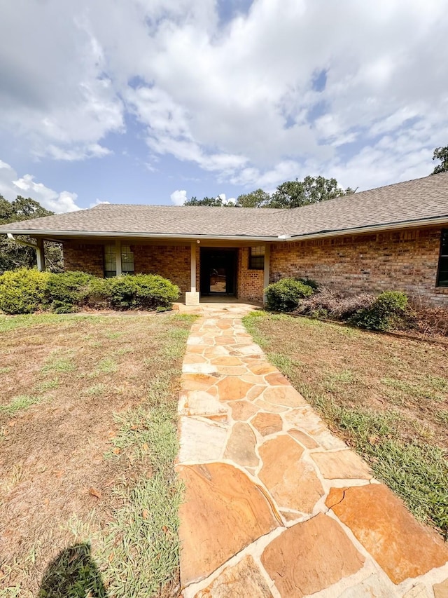 ranch-style home featuring brick siding and roof with shingles