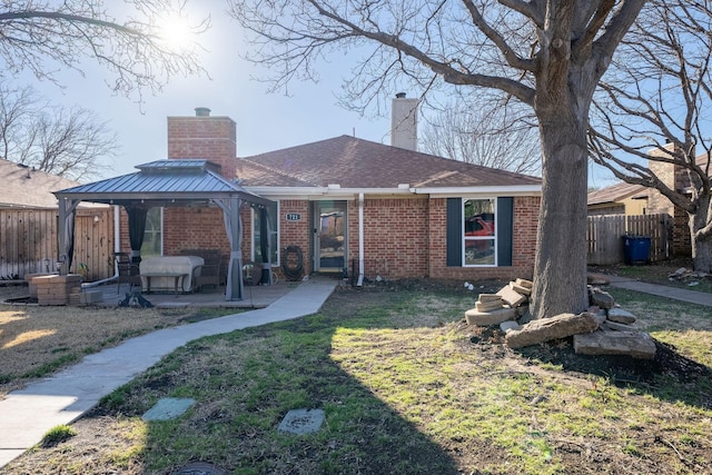 back of property with brick siding, fence, a chimney, and a gazebo