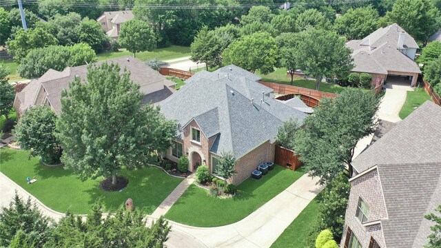 view of front of home featuring a front yard, brick siding, central AC unit, and roof with shingles