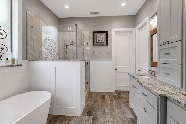 full bathroom with tiled shower, wainscoting, wood finished floors, vanity, and a freestanding tub