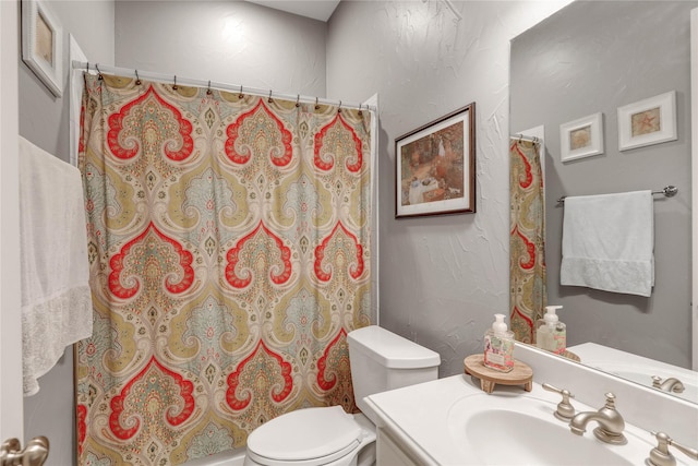 bathroom with curtained shower, a textured wall, vanity, and toilet