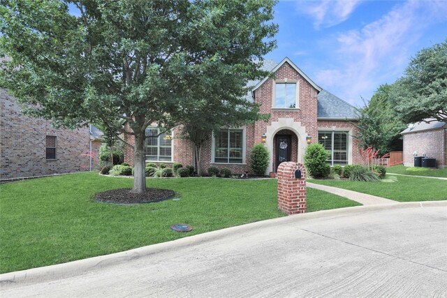 view of front of house with brick siding, roof with shingles, and a front yard