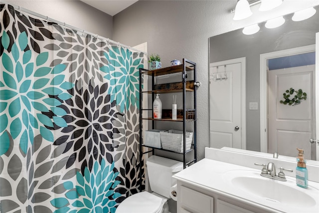 bathroom with a textured wall, vanity, toilet, and a shower with curtain