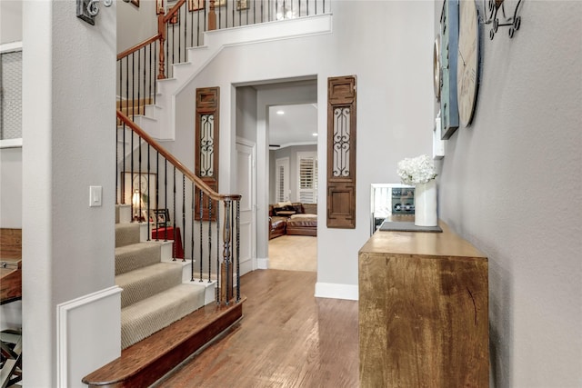 entrance foyer featuring baseboards, a high ceiling, stairway, and wood finished floors