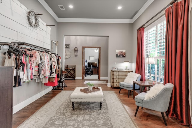 sitting room with visible vents, crown molding, baseboards, and wood finished floors