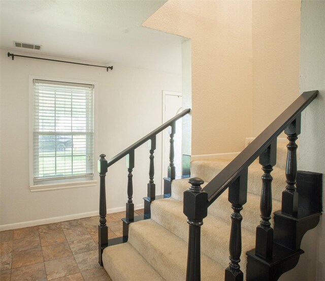 stairs featuring stone finish flooring, visible vents, and baseboards