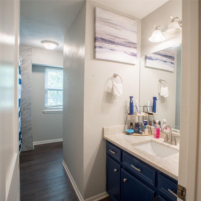 bathroom featuring baseboards, wood finished floors, and vanity