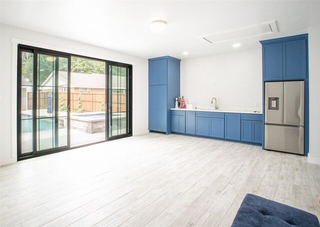 kitchen featuring blue cabinets, stainless steel fridge, light countertops, and light wood-style flooring