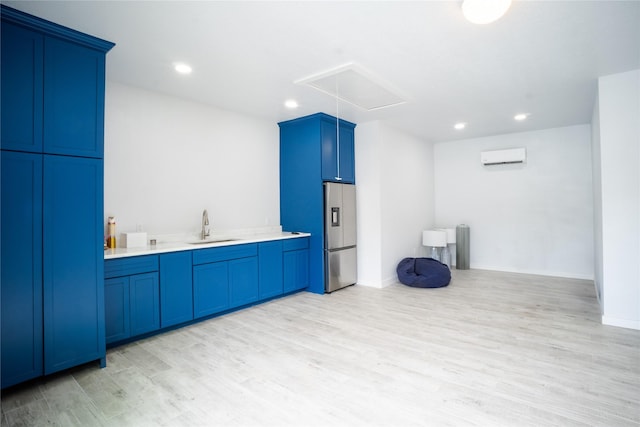 kitchen with light countertops, light wood-style flooring, a sink, a wall mounted air conditioner, and stainless steel fridge with ice dispenser