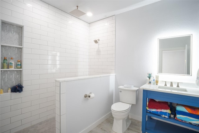 bathroom featuring toilet, vanity, wood finished floors, baseboards, and a walk in shower