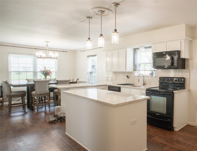 kitchen with backsplash, dark wood-type flooring, a peninsula, black appliances, and a sink