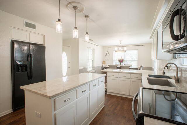 kitchen with dark wood-style floors, visible vents, a sink, light stone countertops, and black appliances