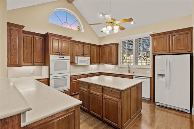 kitchen featuring light countertops, white appliances, wood finished floors, brown cabinets, and a sink