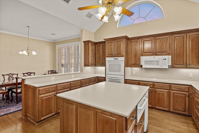 kitchen with white appliances, ceiling fan with notable chandelier, a kitchen island, light wood-style flooring, and brown cabinets
