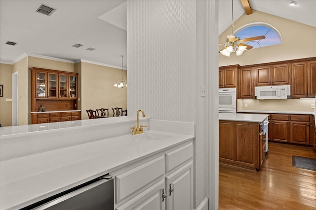kitchen featuring visible vents, white appliances, wood finished floors, a sink, and brown cabinetry
