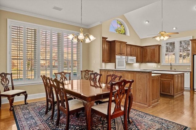 dining area featuring ornamental molding, ceiling fan with notable chandelier, baseboards, visible vents, and light wood-style flooring