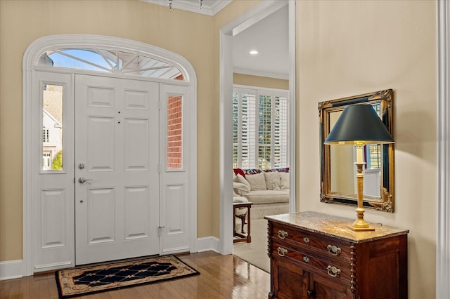 foyer with crown molding, baseboards, and hardwood / wood-style flooring