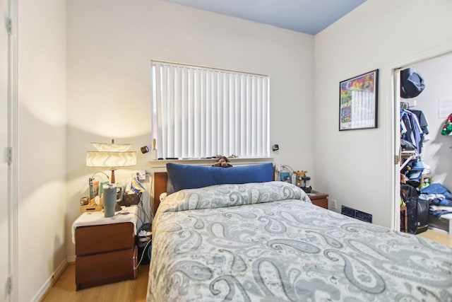 bedroom with a closet, wood finished floors, and baseboards