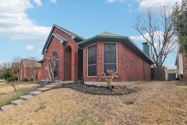 view of front of house with brick siding, a chimney, and a front yard