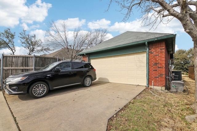 garage with driveway, central air condition unit, and fence