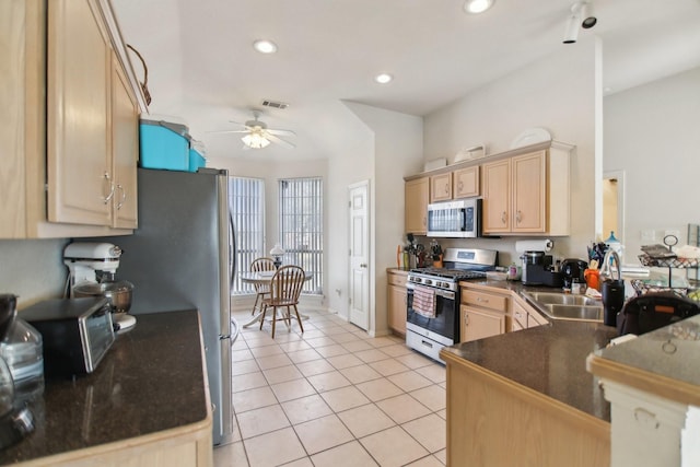 kitchen featuring light tile patterned floors, a sink, appliances with stainless steel finishes, light brown cabinetry, and dark countertops