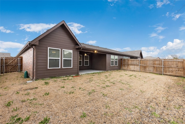 rear view of property featuring a patio area, brick siding, and a fenced backyard