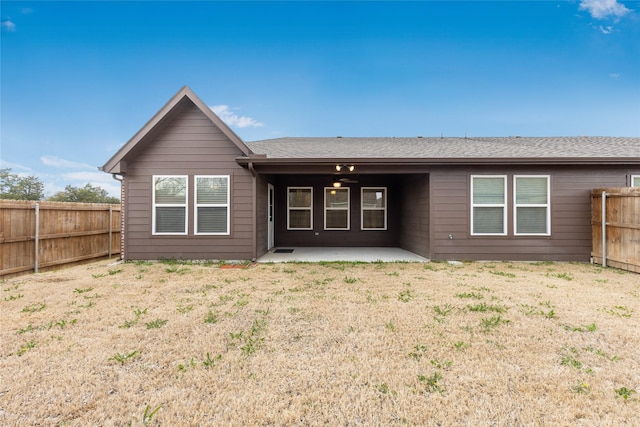 back of property featuring ceiling fan, a fenced backyard, a yard, roof with shingles, and a patio area