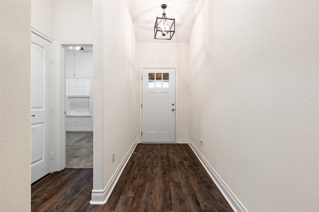 entryway with baseboards, a chandelier, and dark wood-style flooring