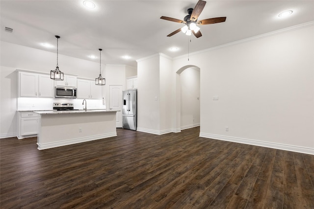 kitchen with visible vents, arched walkways, dark wood-style floors, a kitchen island with sink, and stainless steel appliances