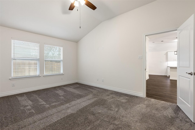 unfurnished room featuring lofted ceiling, baseboards, dark colored carpet, and a ceiling fan