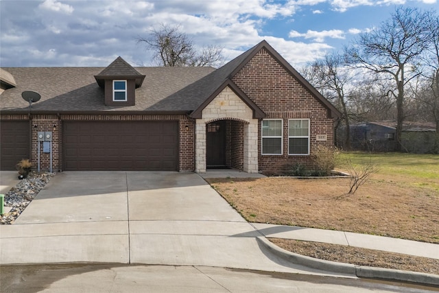 french provincial home featuring brick siding, a shingled roof, concrete driveway, an attached garage, and stone siding