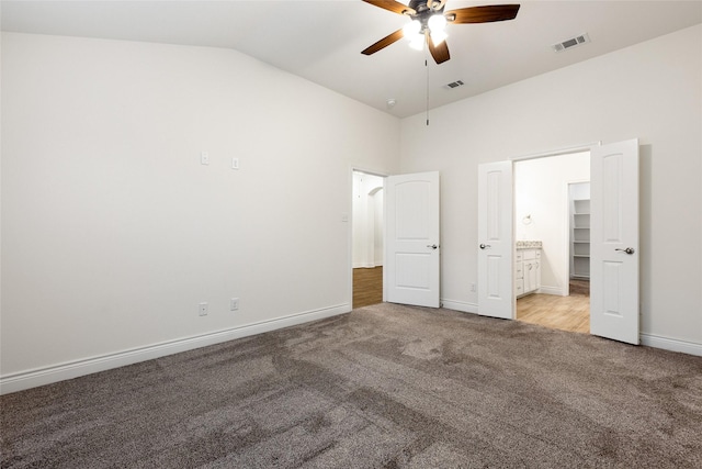 unfurnished bedroom featuring baseboards, visible vents, vaulted ceiling, and light colored carpet