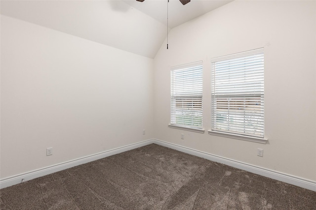 empty room with lofted ceiling, dark colored carpet, ceiling fan, and baseboards