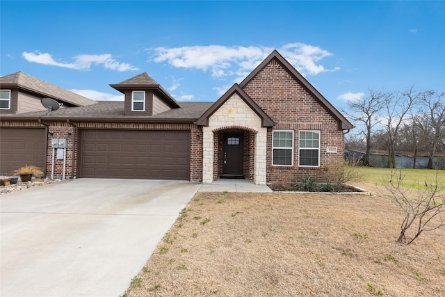 view of front of property with an attached garage, brick siding, stone siding, driveway, and a front yard