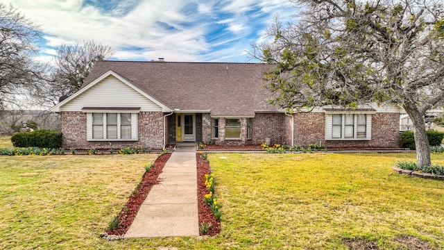 view of front of property with roof with shingles, a front lawn, and brick siding