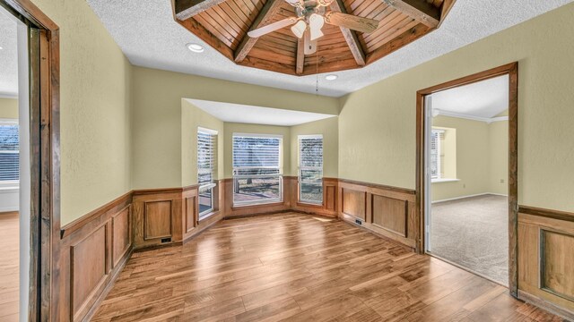 spare room featuring a textured ceiling, wainscoting, a wealth of natural light, and light wood-style floors